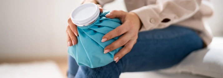 Chiropractic Spokane WA Icing Instructions Woman sitting on sofa and holding a blue ice pack on her knee