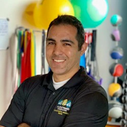 Dr. Paul Ramos wearing a black Applied Health Associates polo shirt and smiling