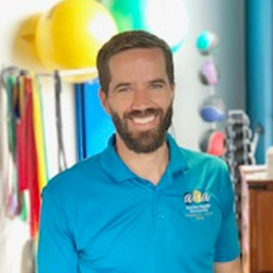 Dr. Taylor Mortlock wearing a blue Applied Health Associates polo shirt and smiling